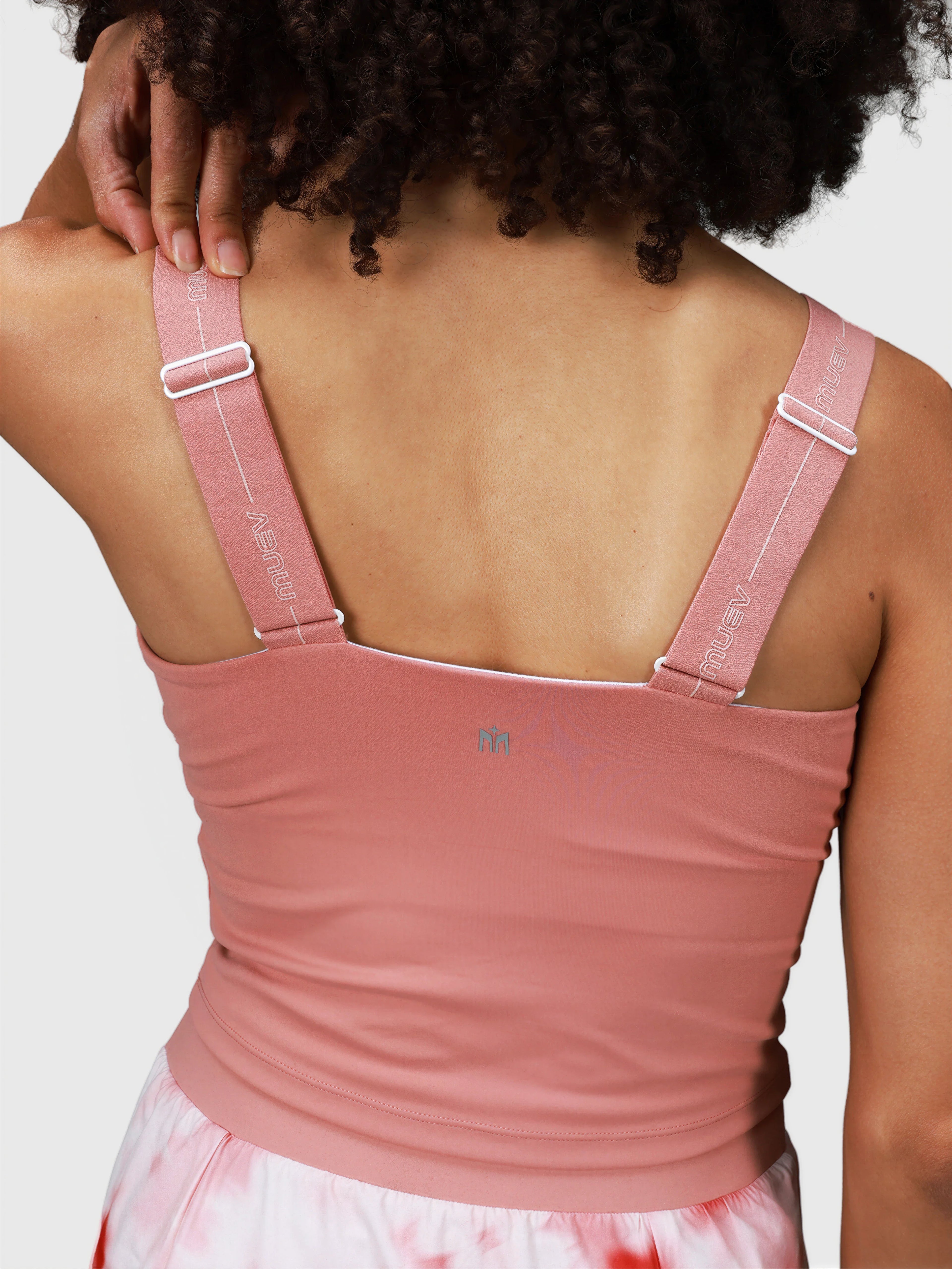 Back view of woman adjusting straps on pink petal Airy Twist Tank by MUEV for padel and pickleball clothing