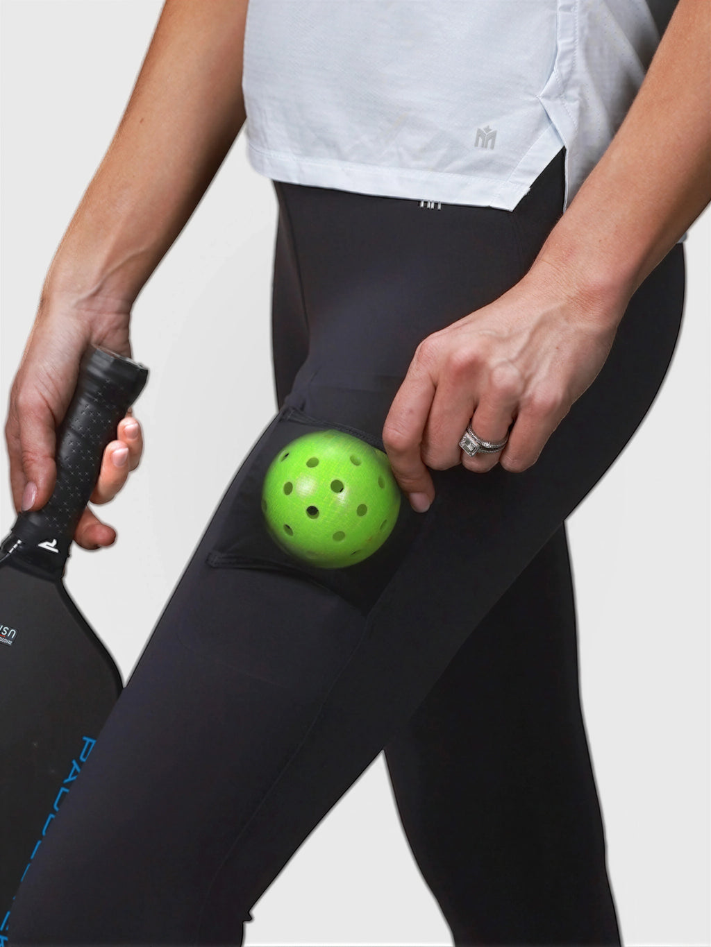 Close-up of black Court Legging by MUEV with side pocket holding green pickleball for padel and pickleball apparel