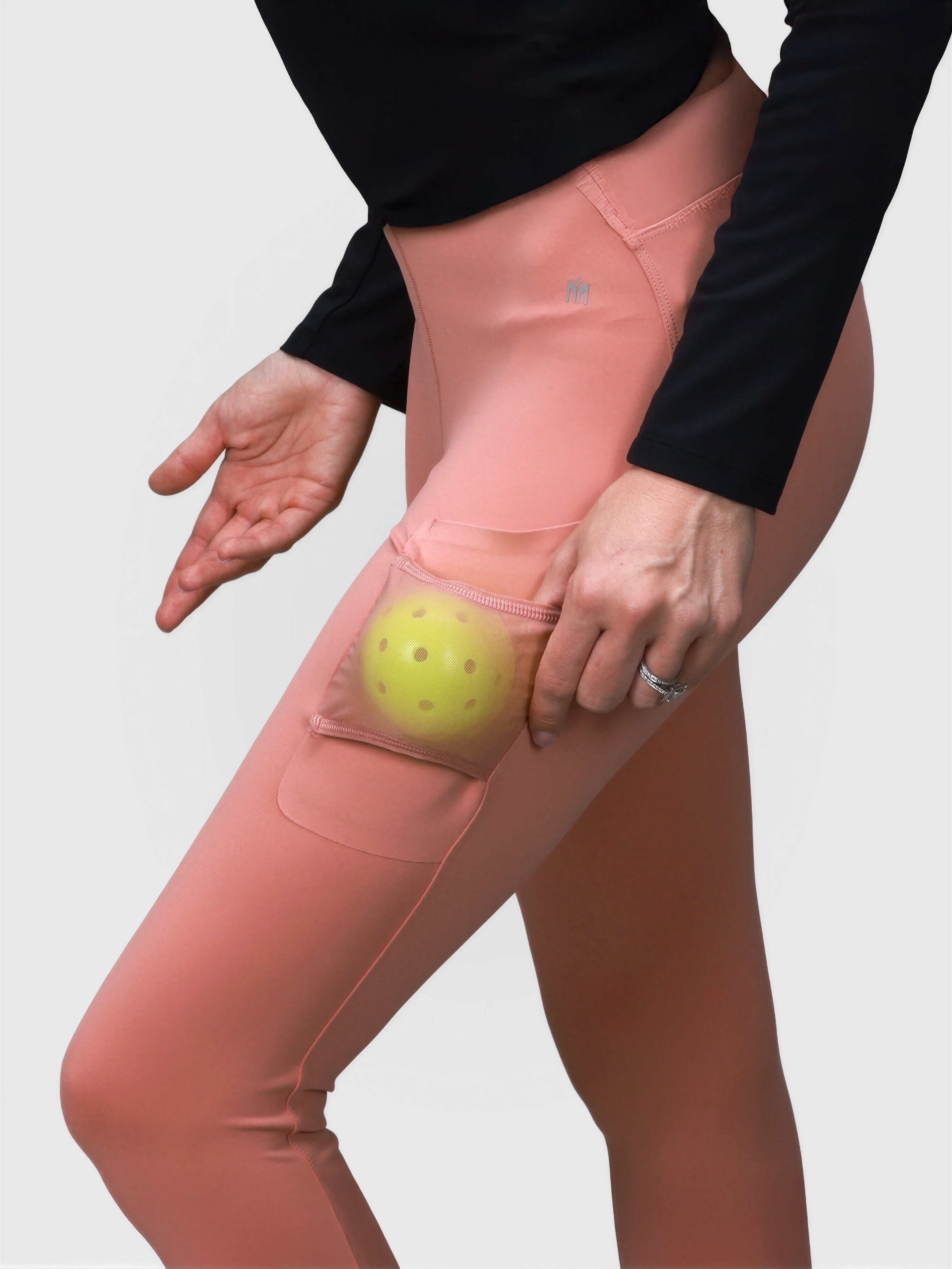 Side view of dusty pink Court Legging with transparent side pocket holding a pickleball ball by MUEV