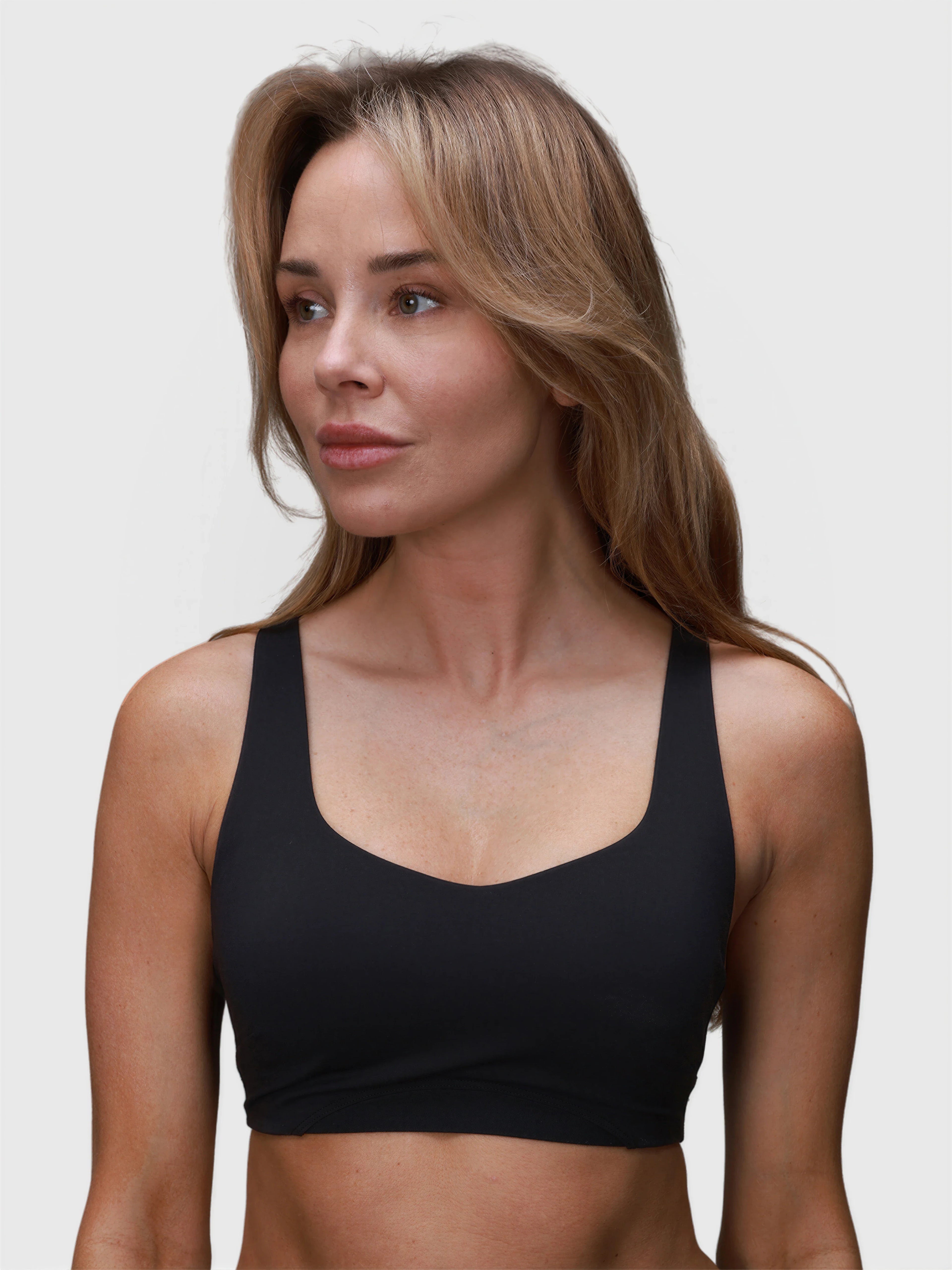 Woman wearing black CrossFlex Sports Bra by MUEV designed for pickleball clothing with supportive fit and wide straps