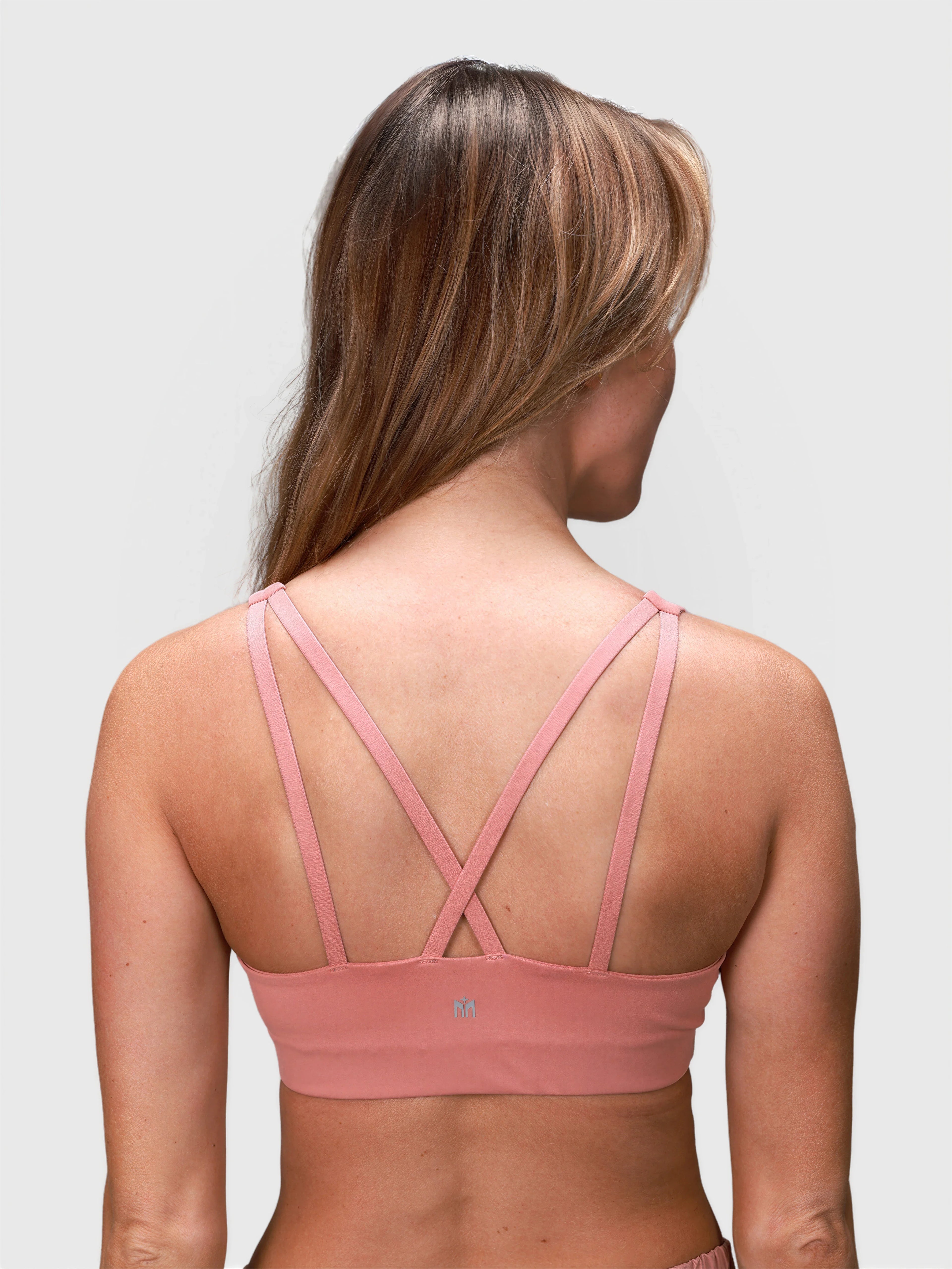 Back view of woman wearing dusty pink CrossFlex Sports Bra by MUEV for pickleball clothing with crossed straps
