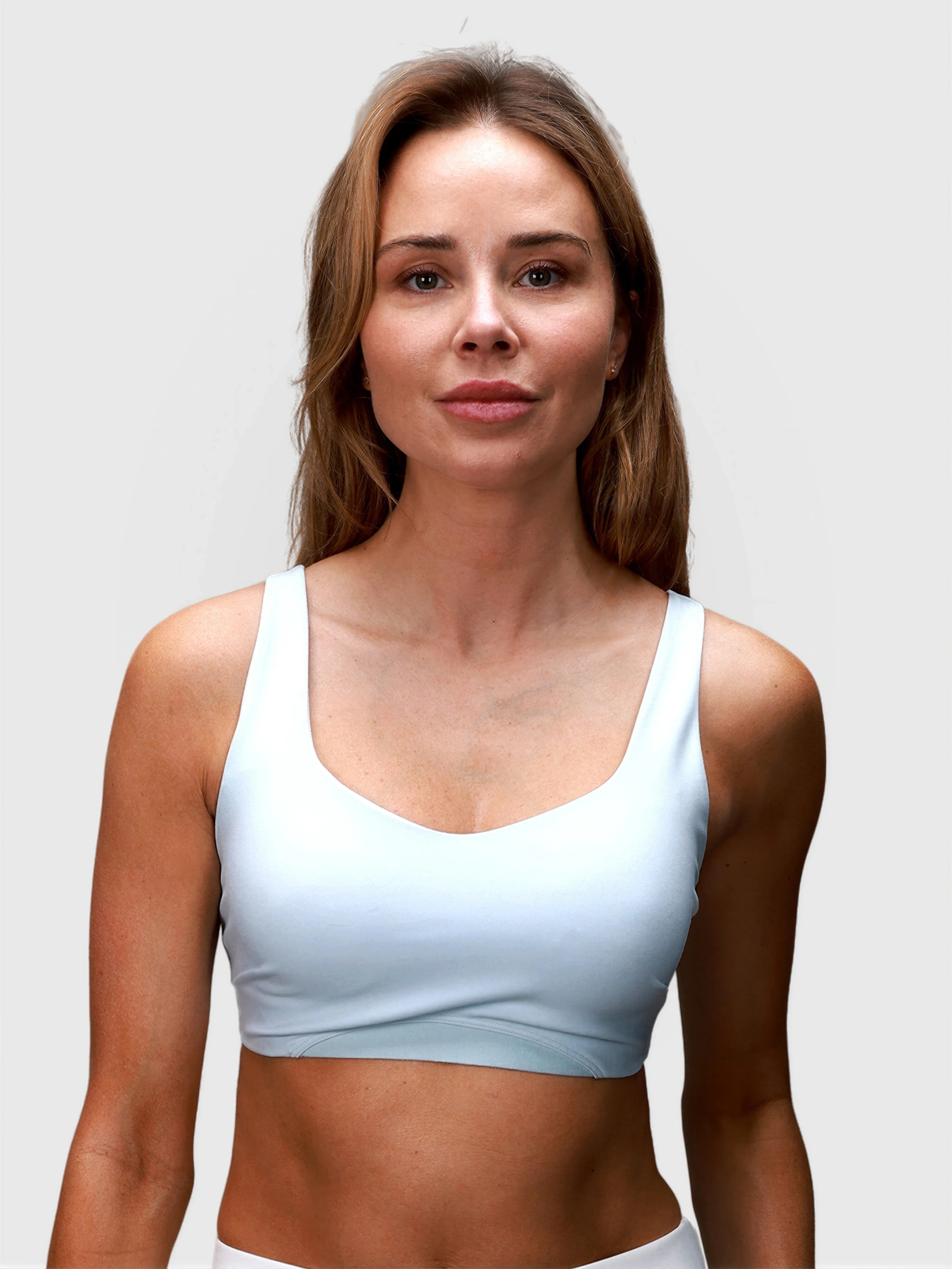Front view of woman wearing ice blue CrossFlex Sports Bra by MUEV designed for pickleball clothing with supportive fit