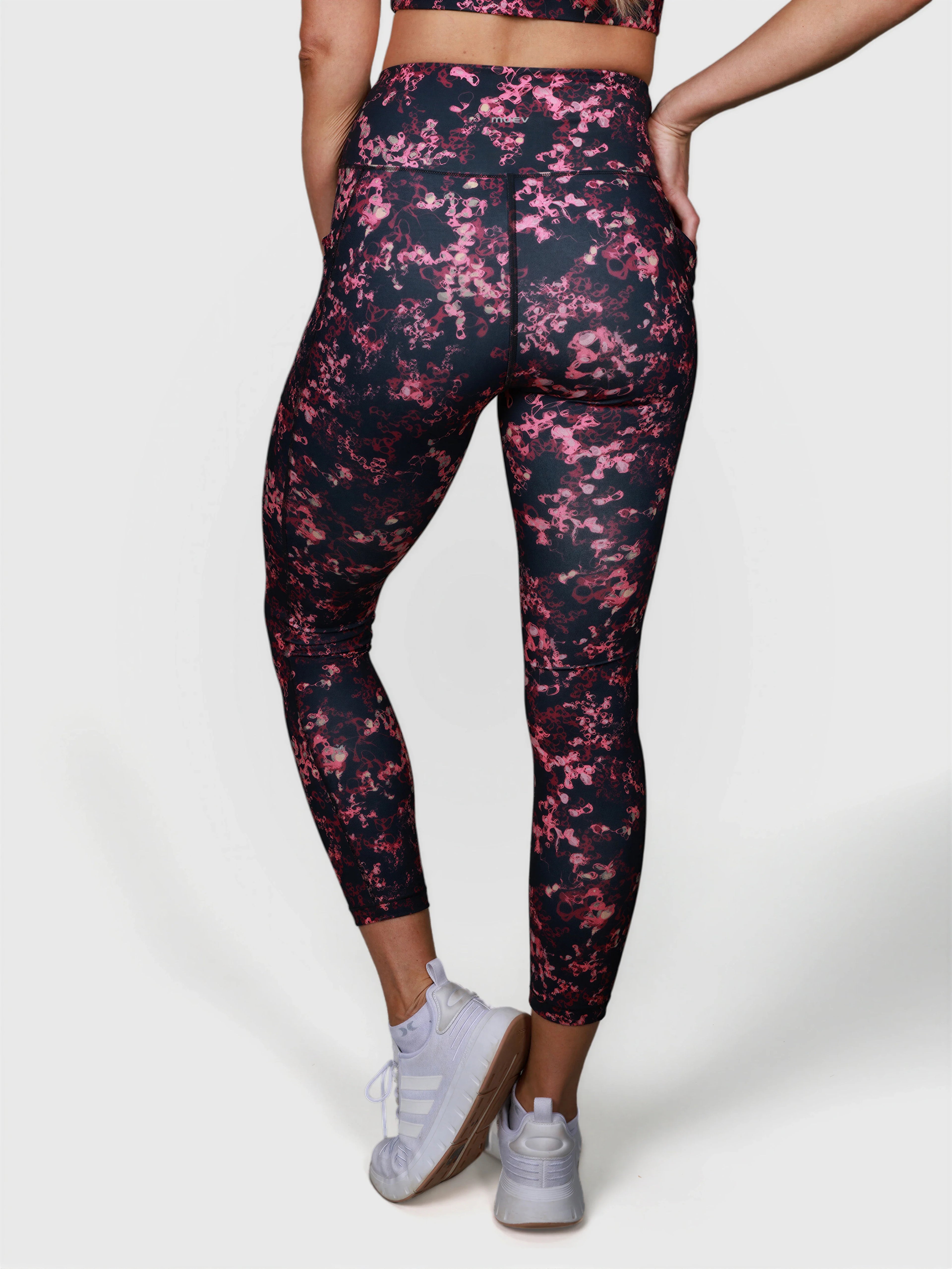 rear view of woman wearing black and pink patterned V Cross Over Leggings by MUEV for padel apparel