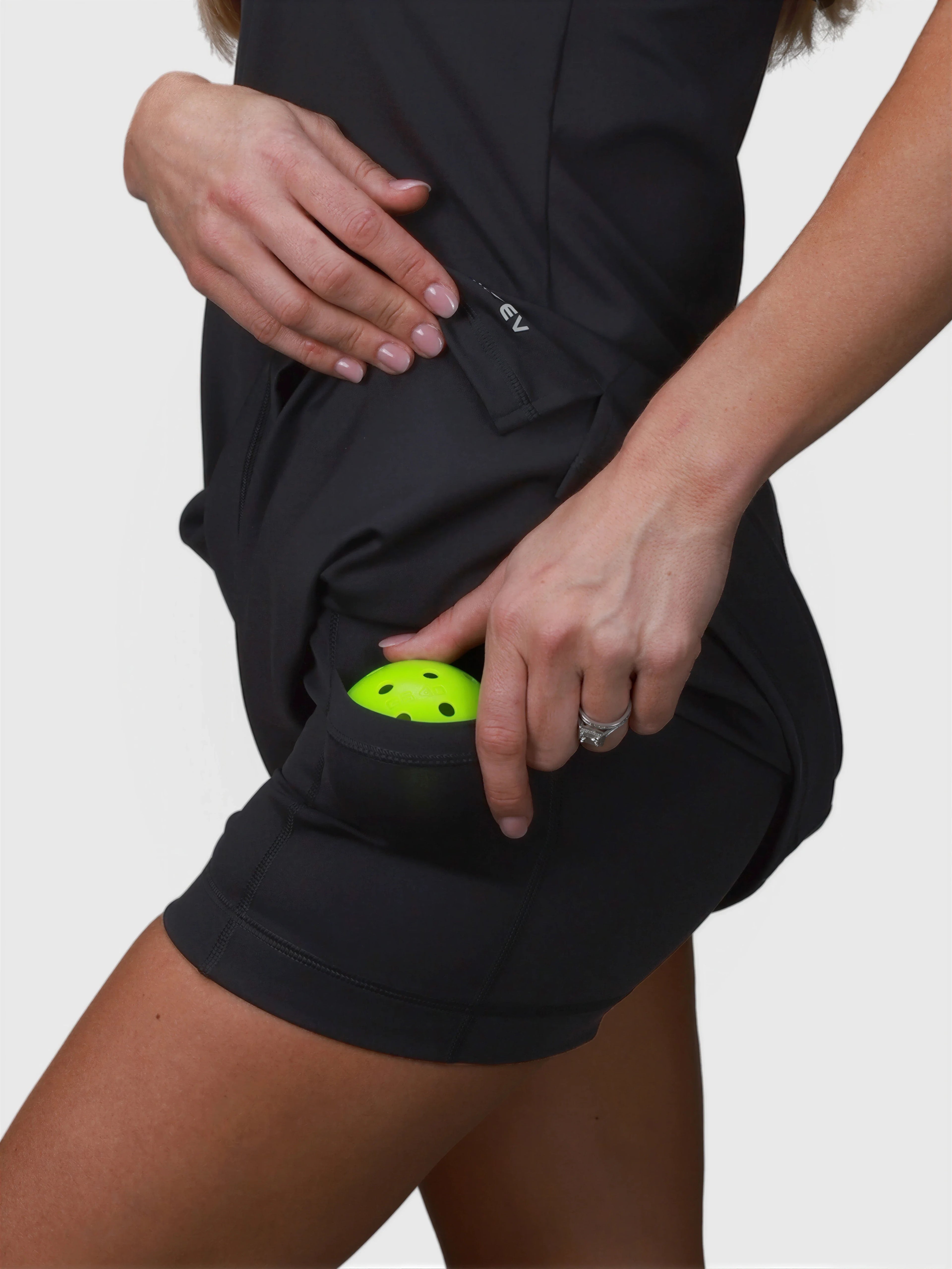Close-up of black Double V Dress by MUEV showing side pocket with bright pickleball ball for pickleball apparel