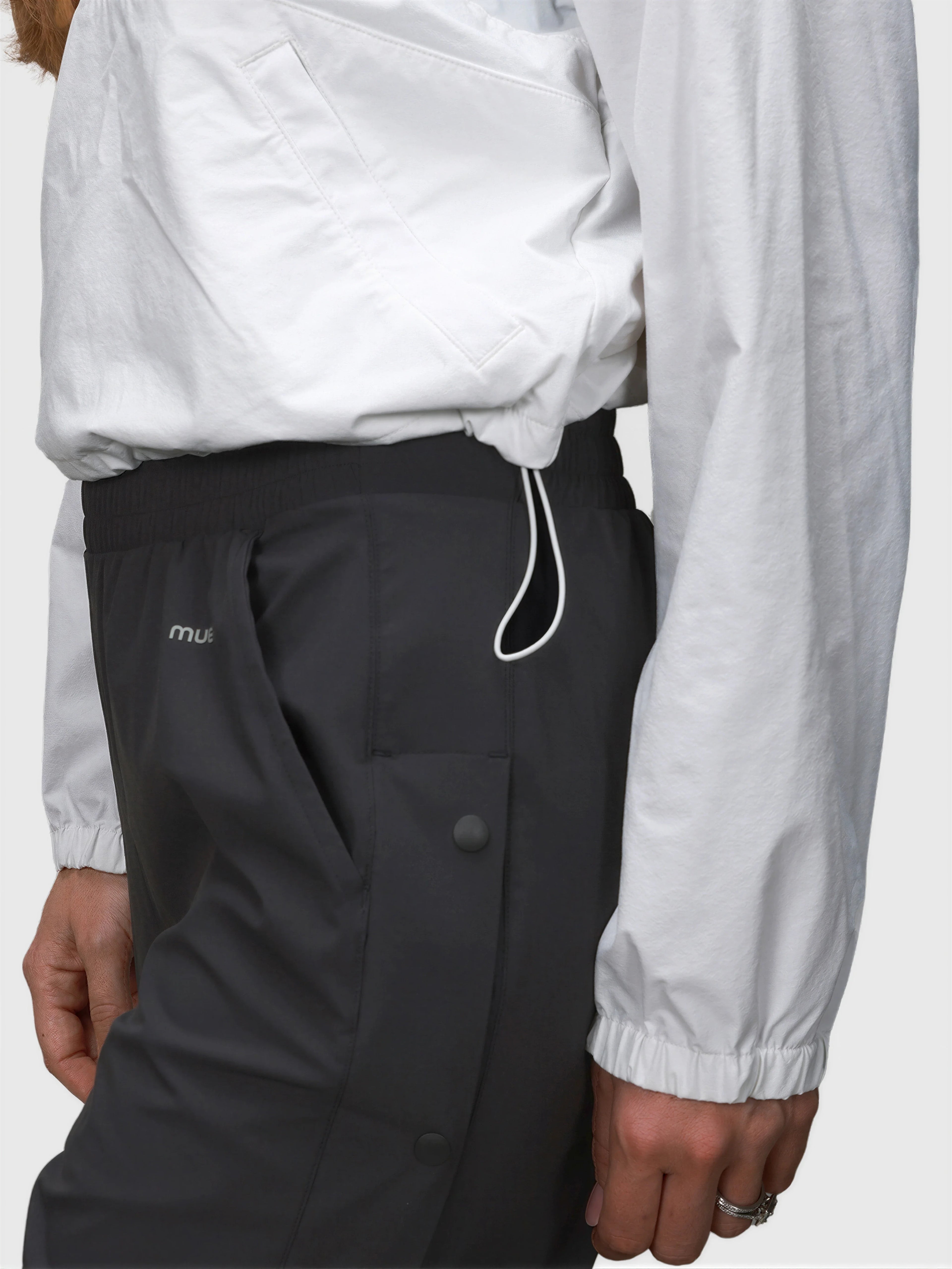 Side view of white E Sas Crop Jacket by MUEV paired with black pants designed for padel and pickleball clothing