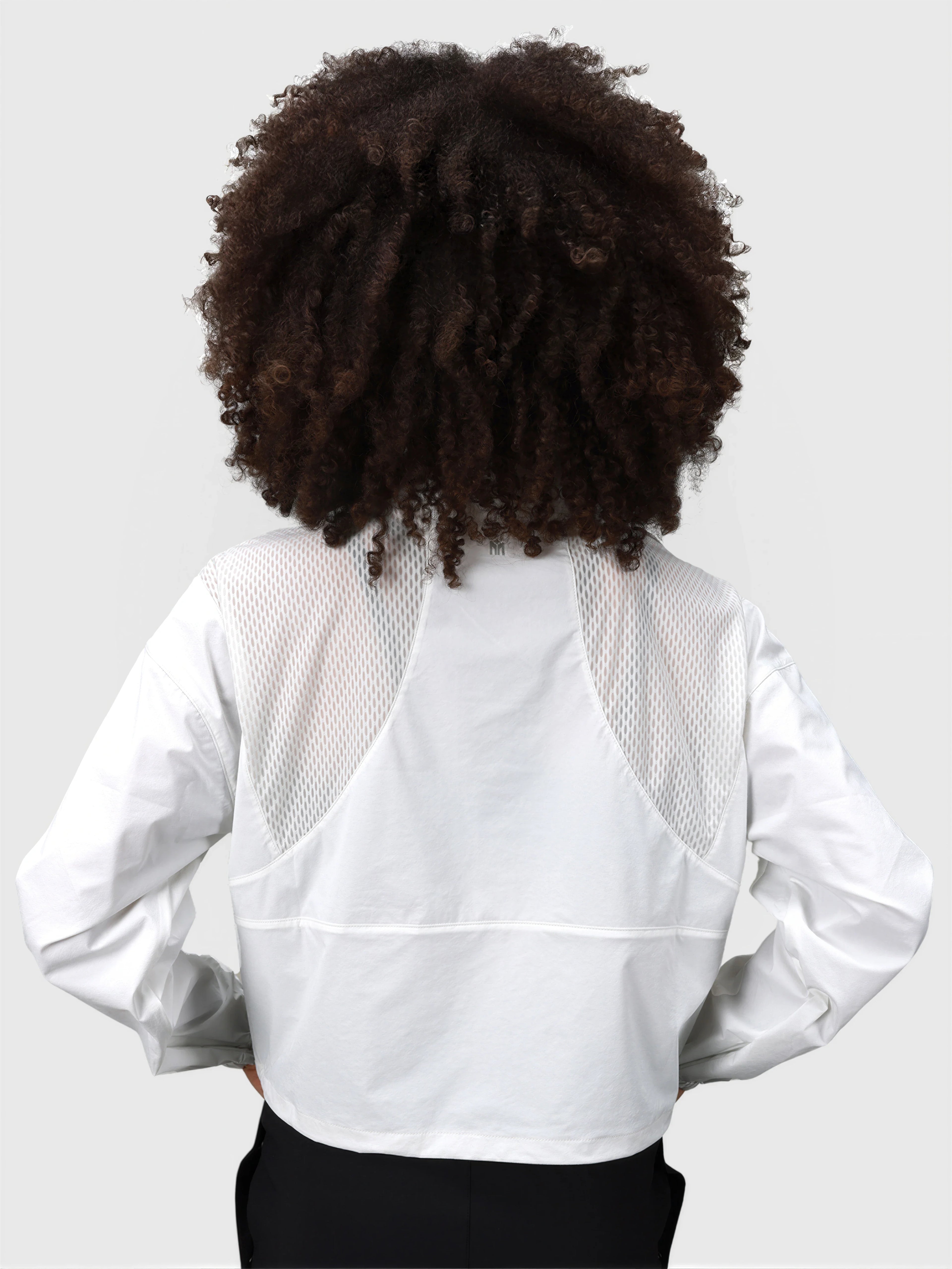 Back view of white E Sas Crop Jacket by MUEV featuring mesh panels, ideal for padel and pickleball apparel