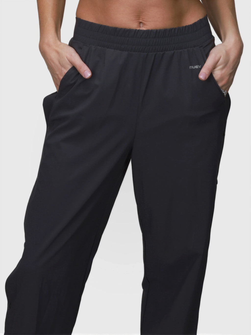 Close-up of person wearing black E Sas Tear Away Pant by MUEV with elastic waistband and side pockets for padel clothing