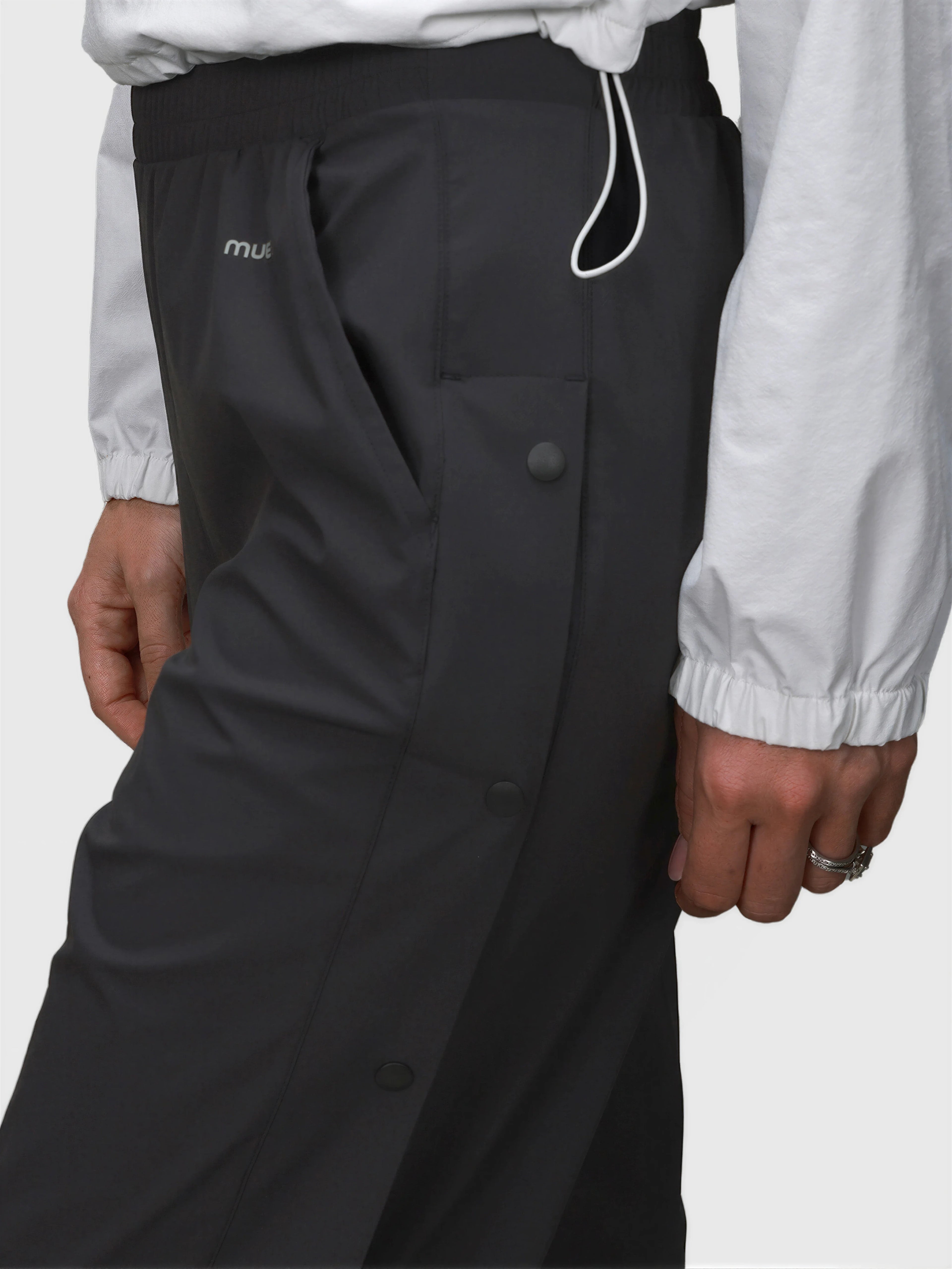 Close-up of black E Sas Tear Away Pant by MUEV with snap buttons and elastic waistband for padel and pickleball apparel