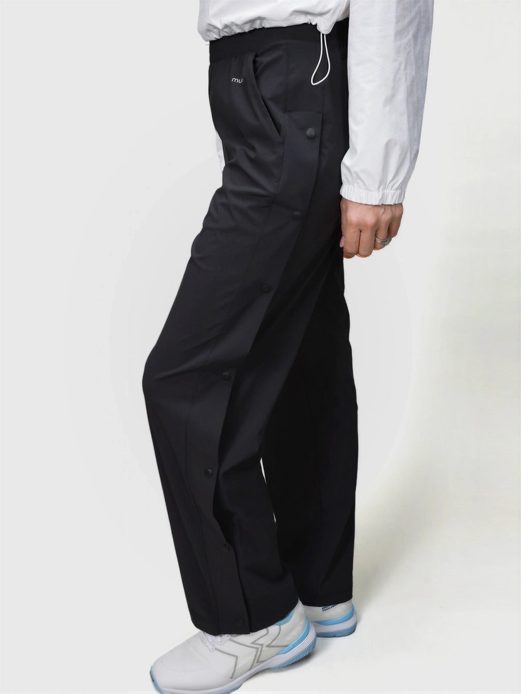 Side view of person wearing black E Sas Tear Away Pant by MUEV for pickleball clothing with button details and elastic waistband