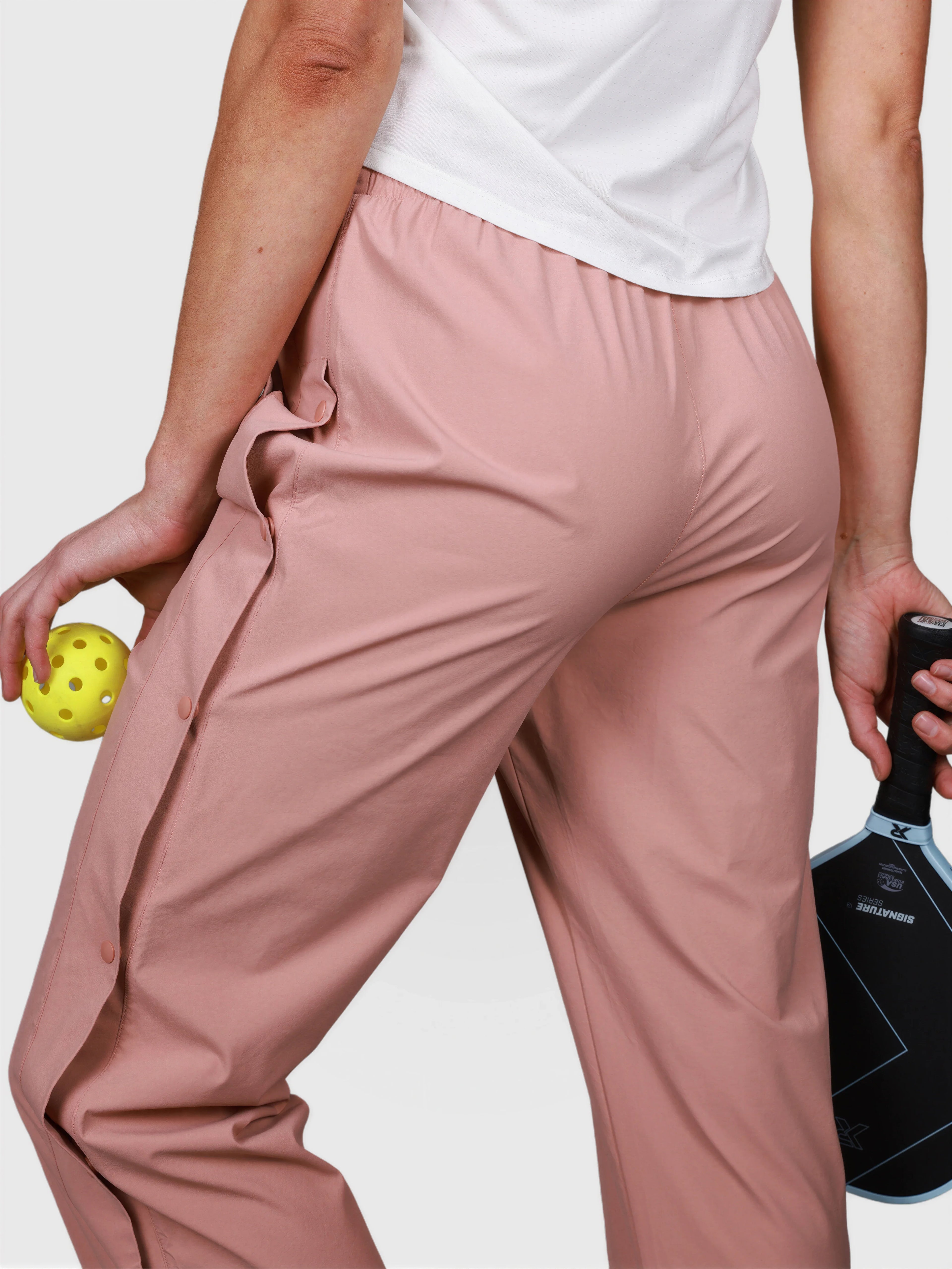 Rear view of person wearing dusty pink E Sas Tear Away Pant by MUEV for pickleball apparel with elastic waistband and side buttons