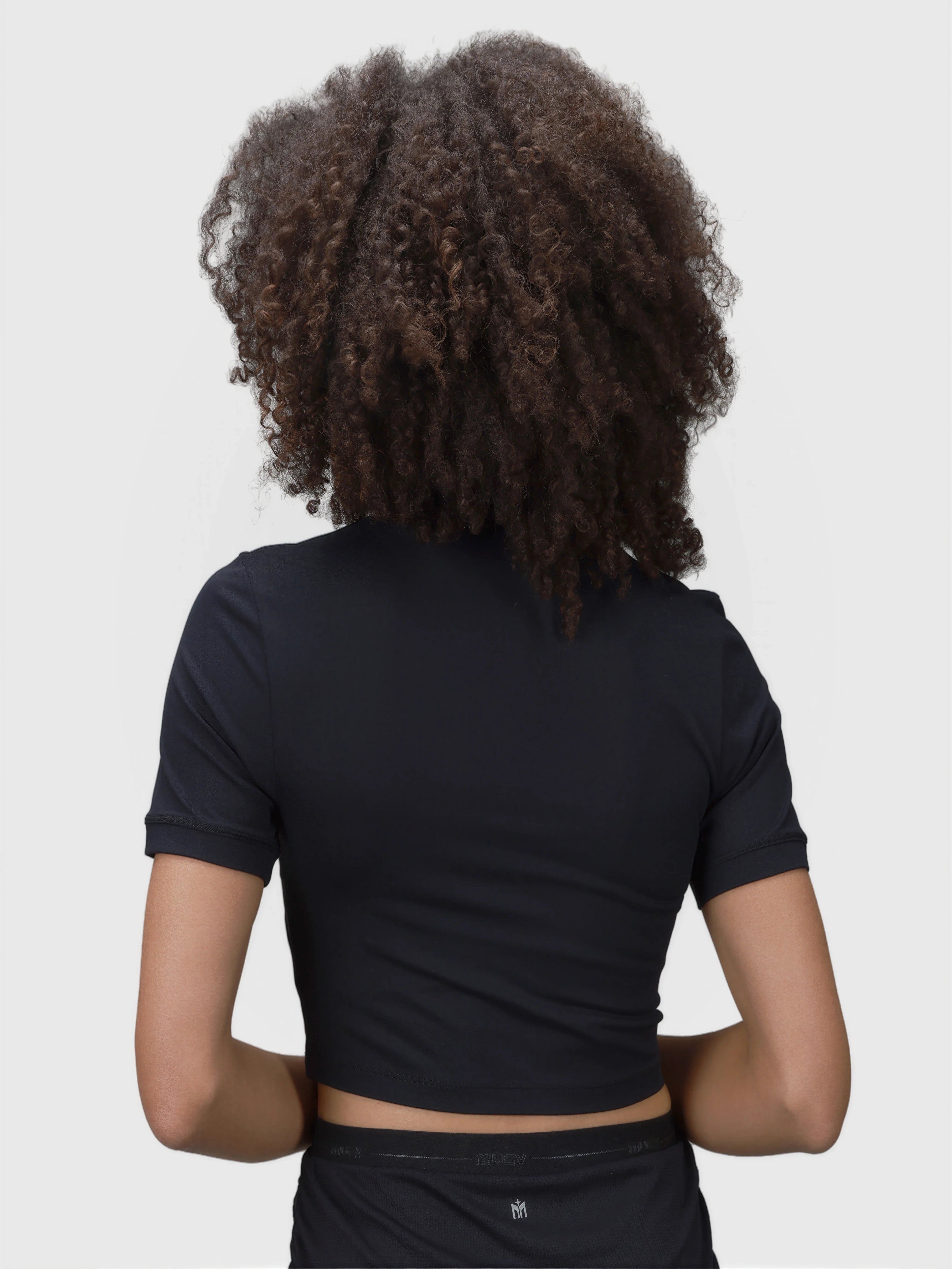 Back view of woman wearing black Kamryn Cropped Tee by MUEV for pickleball clothing with short sleeves and fitted style