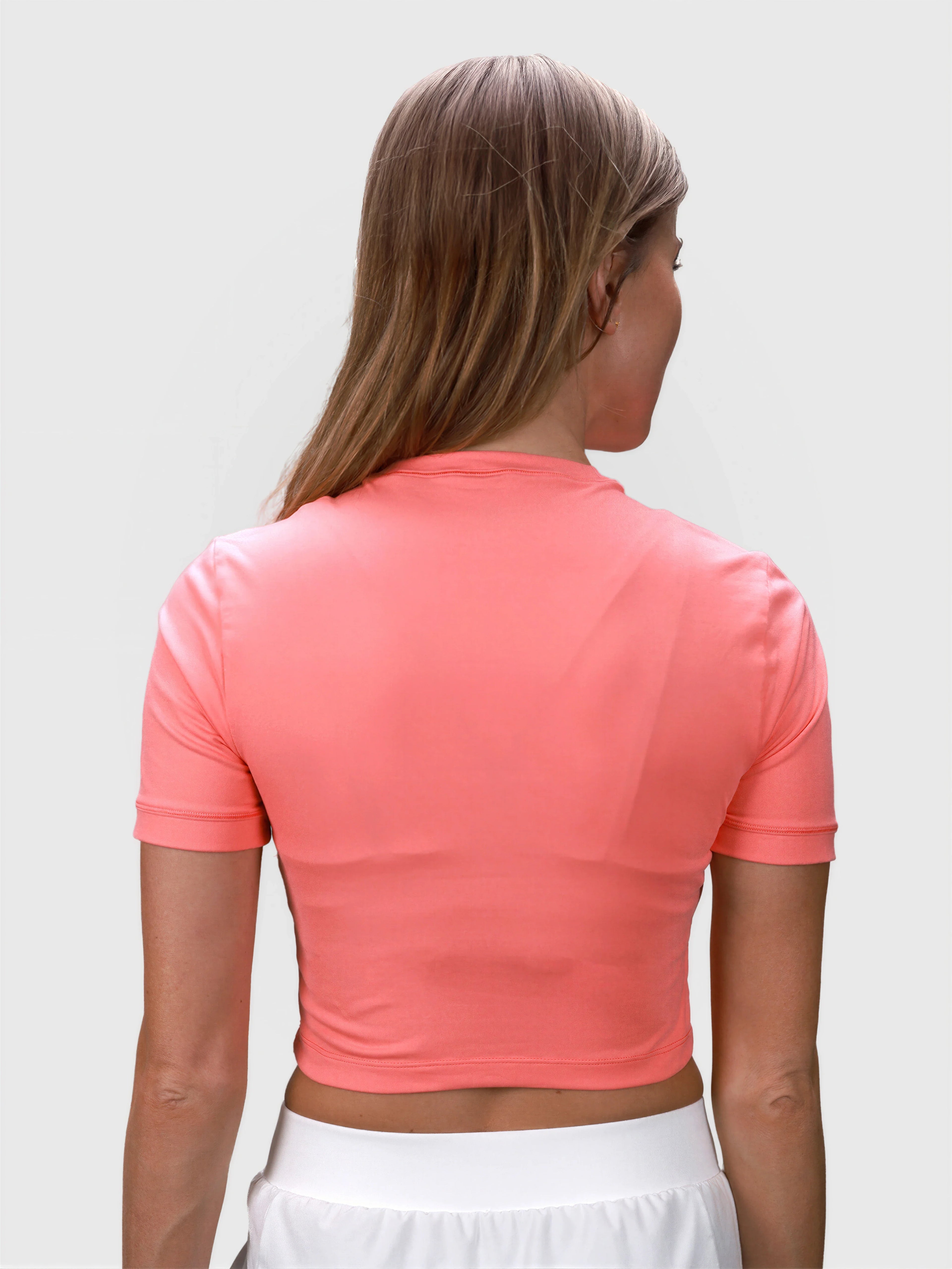 Rear view of coral Kamryn Cropped Tee by MUEV styled for pickleball clothing with short sleeves and cropped fit