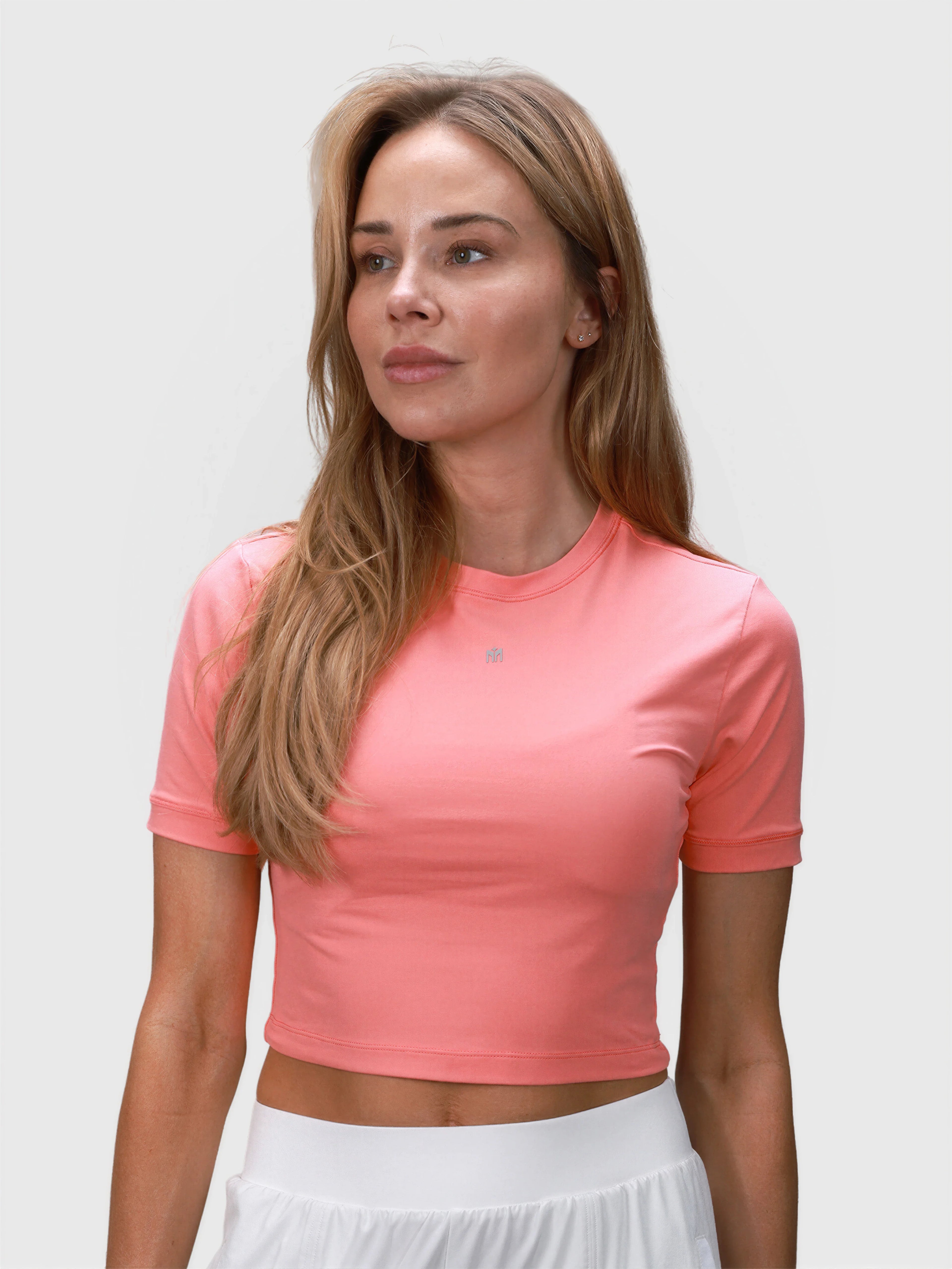 Woman wearing coral Kamryn Cropped Tee by MUEV designed for pickleball clothing with short sleeves and fitted style
