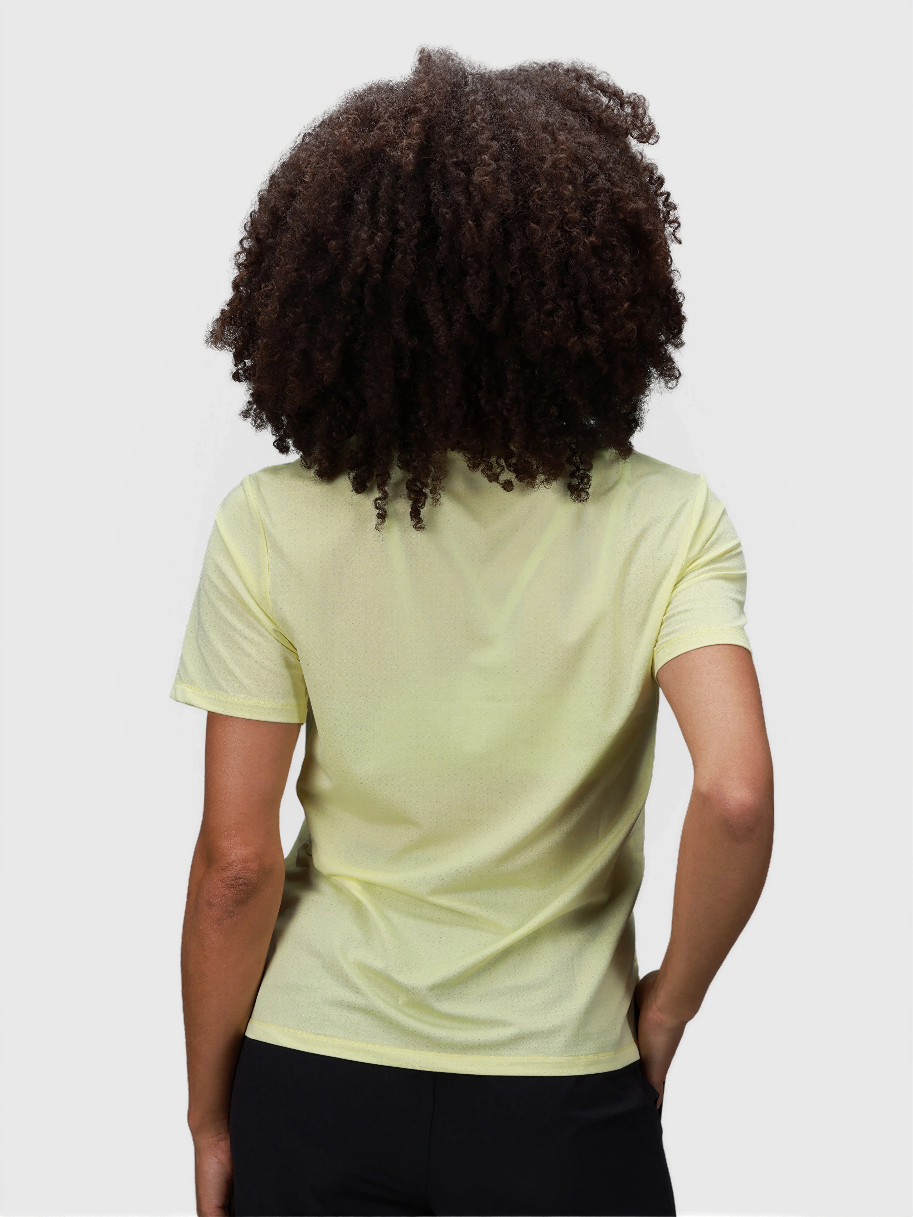Rear view of woman wearing citron PowerMove Performance Tee by MUEV for padel and pickleball apparel