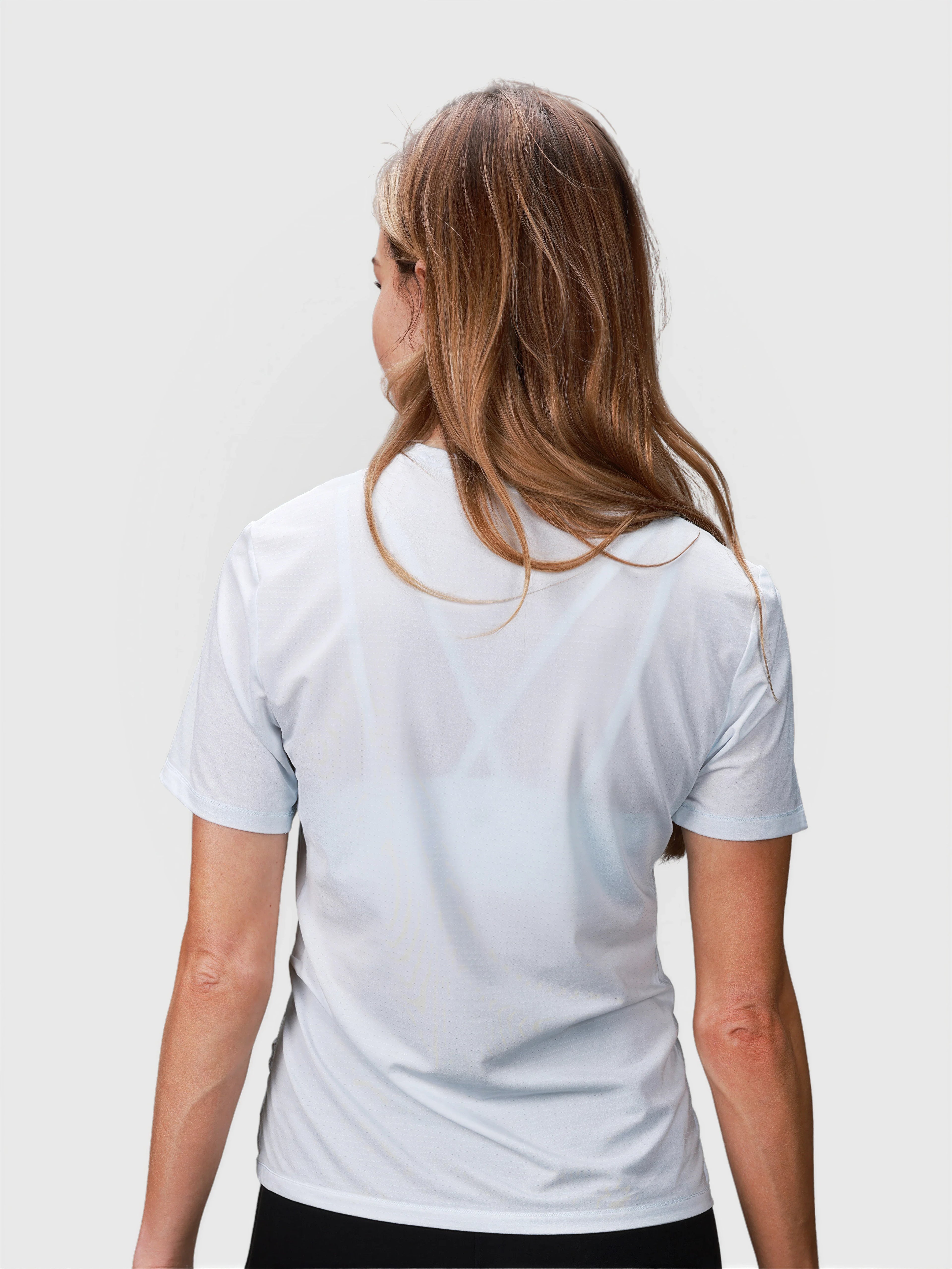 Rear view of woman wearing white PowerMove Performance Tee by MUEV for padel and pickleball clothing