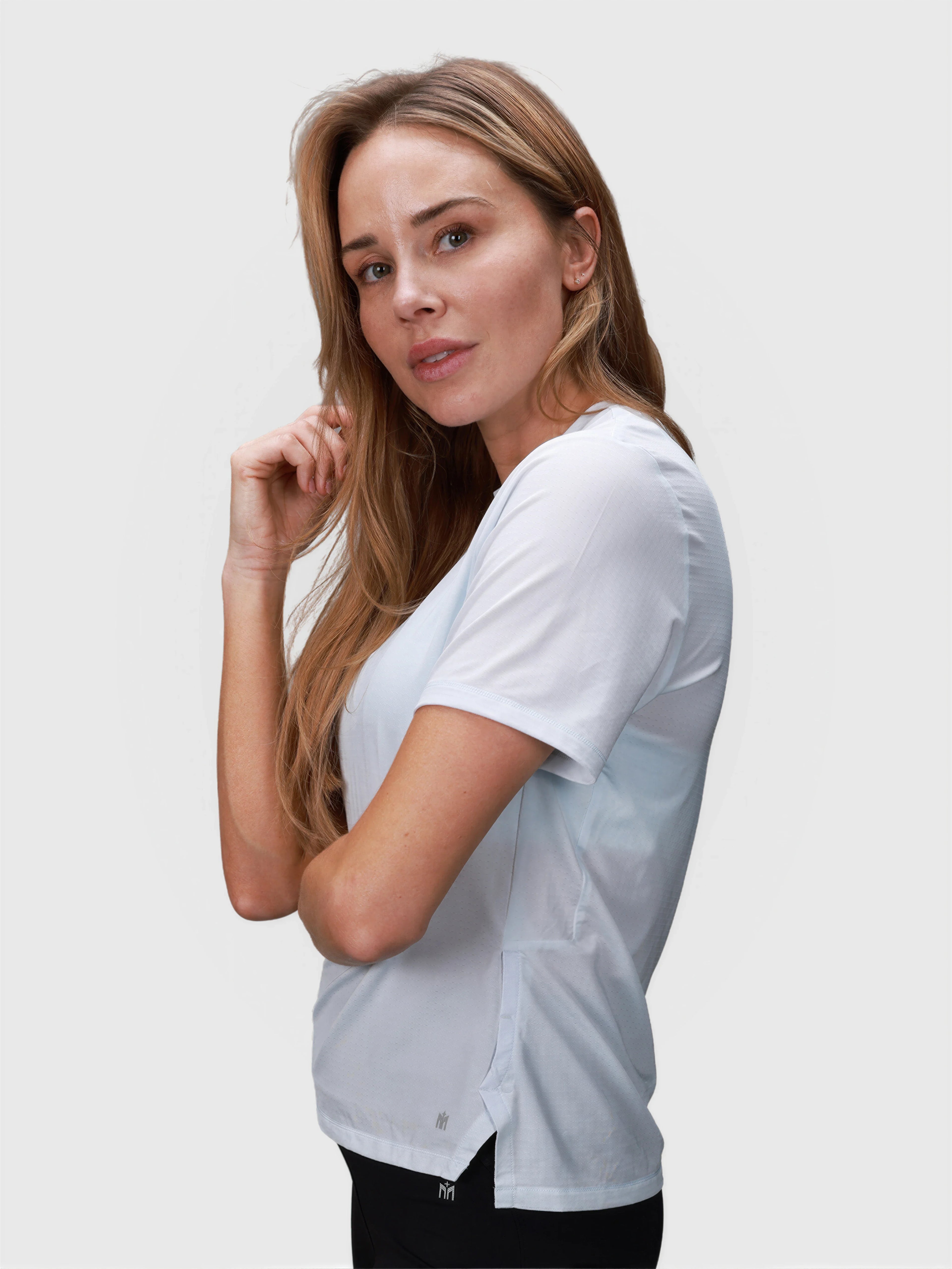 Side view of woman modeling ice blue PowerMove Performance Tee by MUEV for padel and pickleball apparel