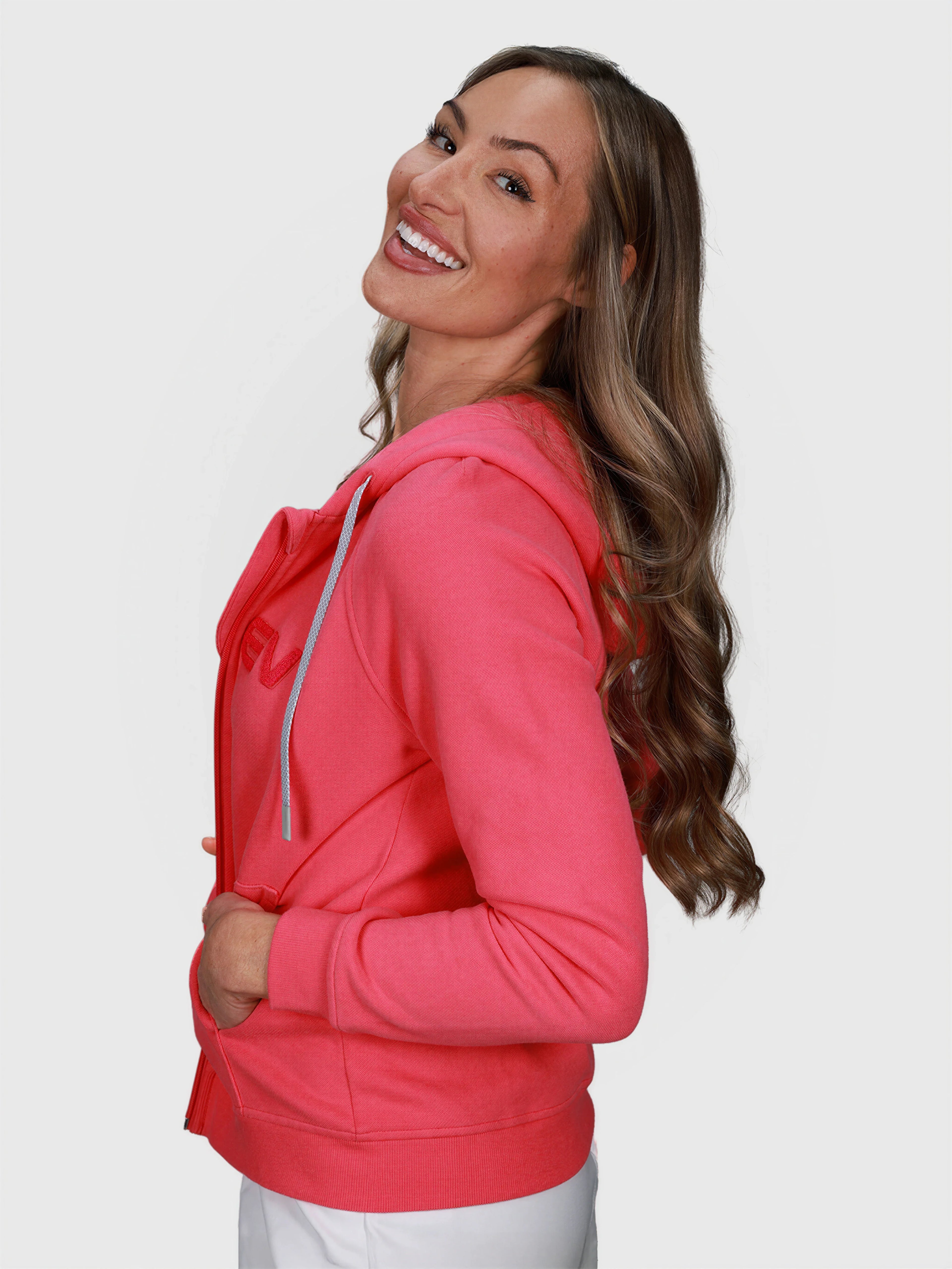 Smiling woman in pink Women's Off Court Full Zip Hoodie by MUEV for padel and pickleball clothing